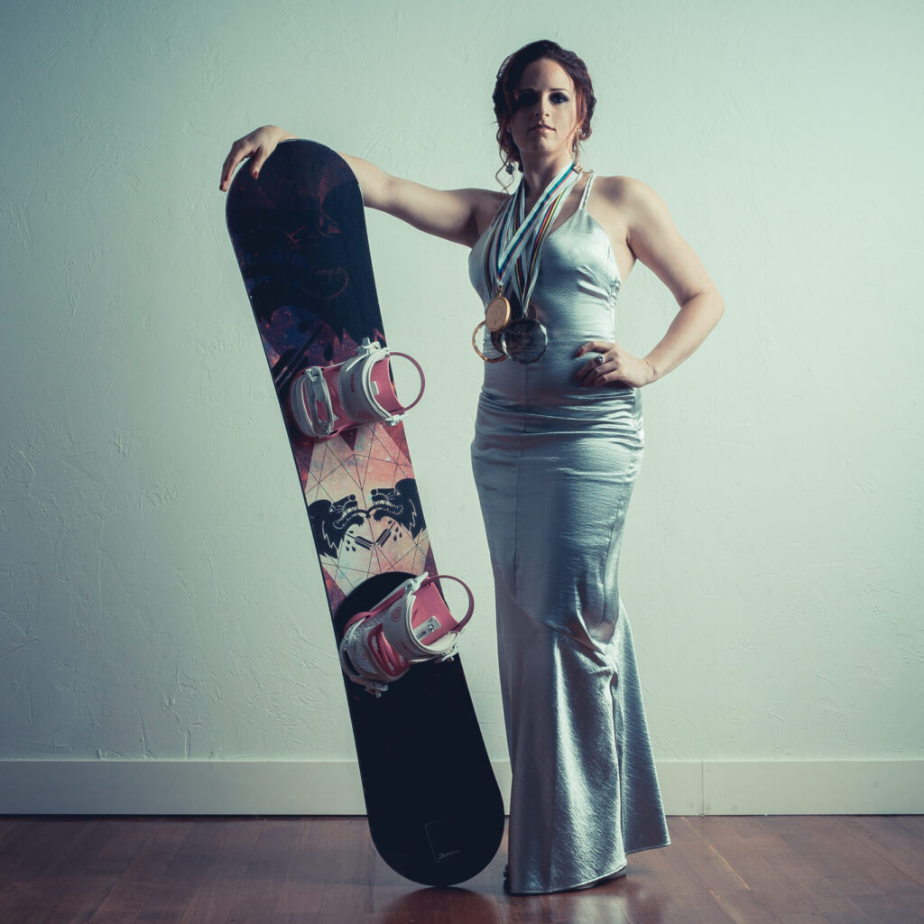 Nicole Roundy stands with custom Donek raceboard and world cup medals